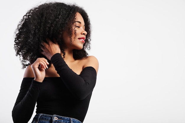 Mulher negra tocando seu cabelo encaracolado