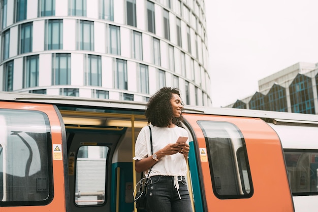 Mulher negra, usando telefone celular no metrô de londres