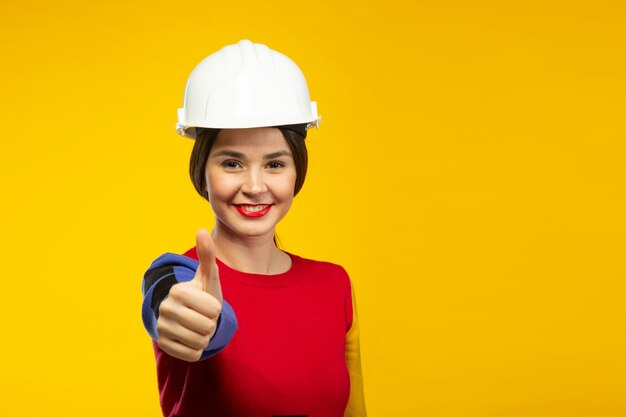 Mulher no capacete de construção mostra os polegares