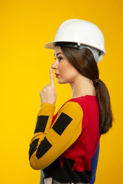 Mulher no capacete de construção mostra para ficar em silêncio
