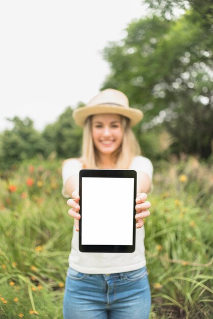 Mulher no jardim mostrando tablet com tela em branco