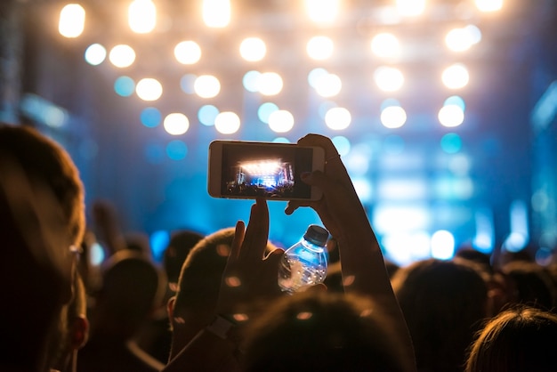 Mulher no meio da multidão tirando foto do palco no festival de música