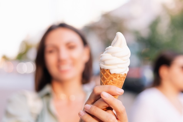 Mulher no pôr do sol de verão tomando sorvete na rua da cidade