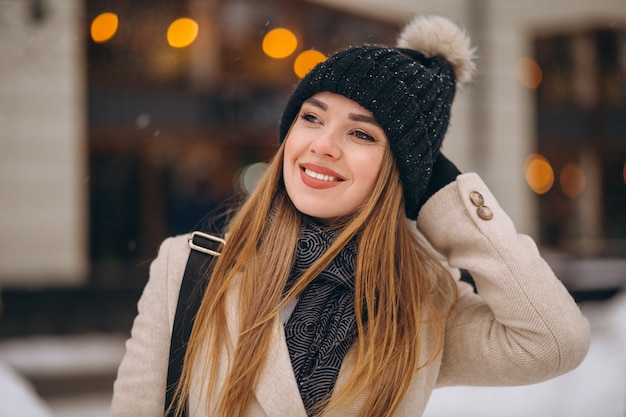 Mulher no revestimento do lado de fora do café em uma rua de inverno