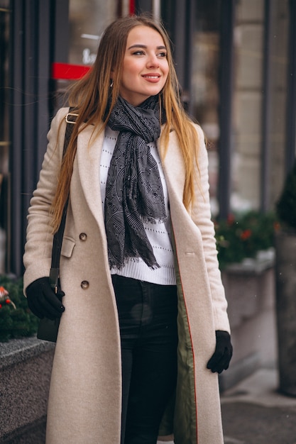 Foto grátis mulher no revestimento do lado de fora do café em uma rua de inverno