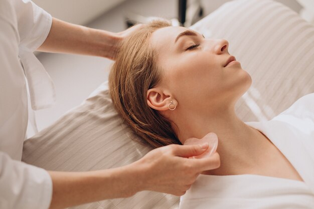 Mulher no salão fazendo tratamento de beleza com pedra gua sha