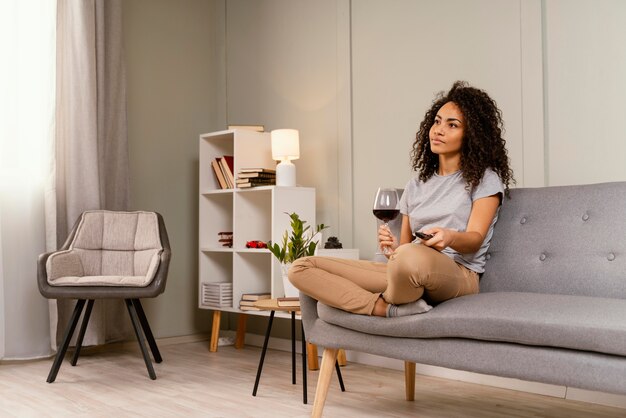 Mulher no sofá assistindo tv e bebendo vinho