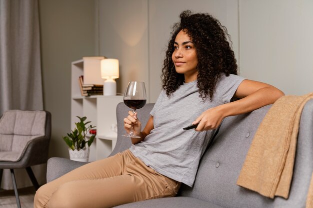 Mulher no sofá assistindo tv e bebendo vinho