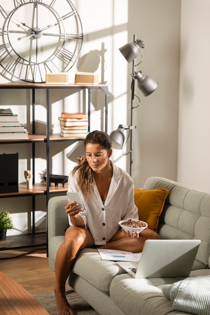 Foto grátis mulher no sofá comendo na frente do laptop