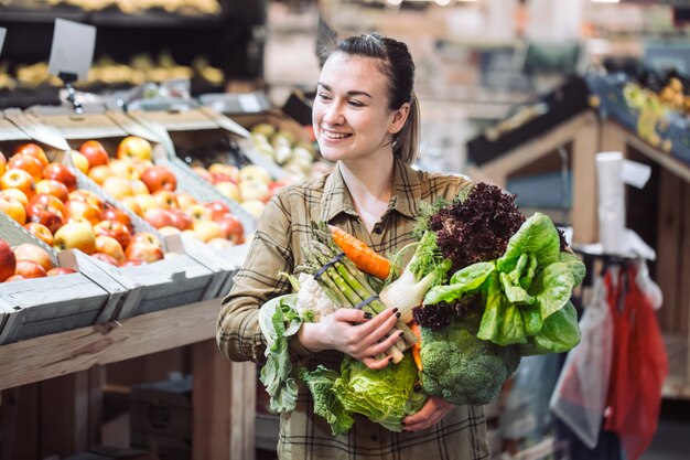 Mulher no supermercado. Mulher jovem e bonita às compras em um supermercado e comprar legumes orgânicos frescos