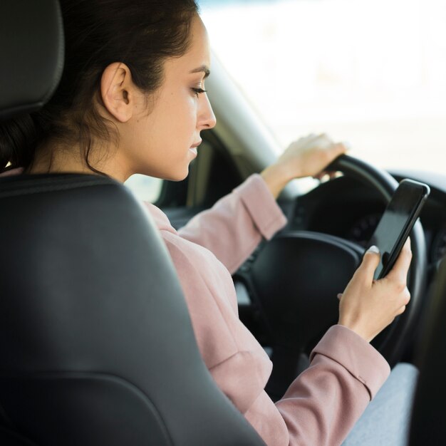 Mulher no volante usando seu telefone