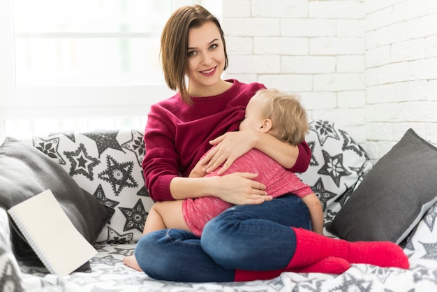 Mulher nova com o bebê no sofá