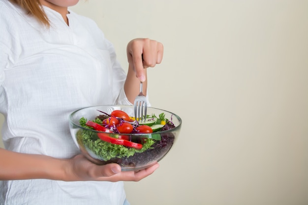 Mulher nova que come a salada saudável