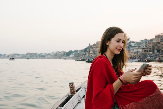 Mulher ocidental em um texting de barco do rio Ganges