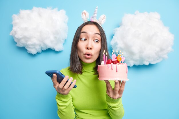 mulher olha maravilhada com bolo festivo faz telefonema para amigos e convida para festa de aniversário vestida