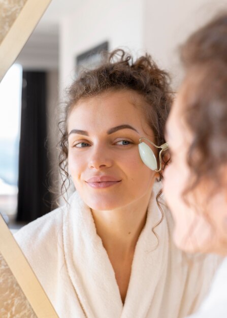 Mulher olhando no espelho e fazendo massagem facial