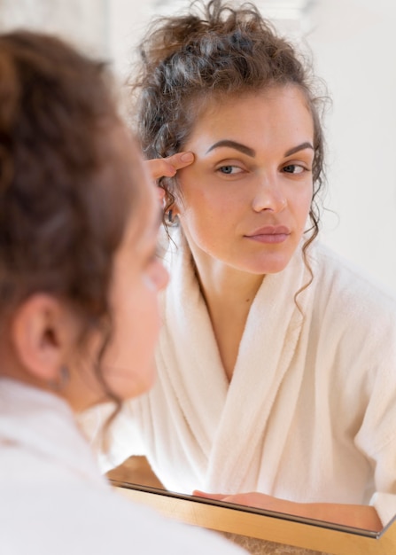 Mulher olhando no espelho e fazendo uma rotina de beleza facial