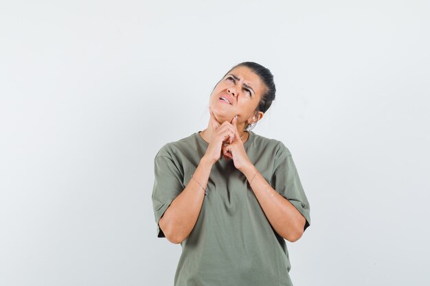 mulher olhando para cima em t-shirt e parecendo pensativa.