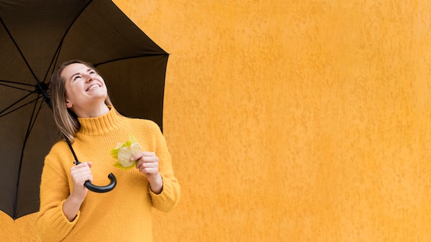 Mulher olhando para cima, segurando um guarda-chuva com espaço de cópia