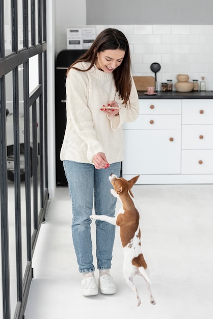 Mulher olhando para smartphone e dando deleites de cachorro