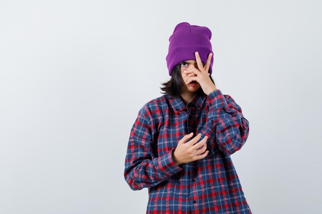 Foto grátis mulher olhando pelo gorro entre os dedos e falando sério