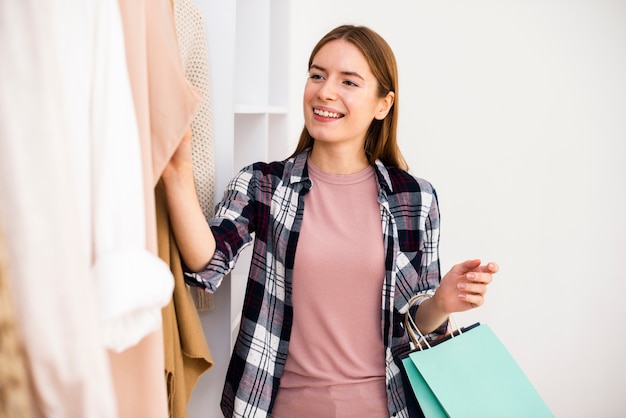 Mulher olhando roupas com sacos na mão