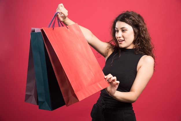 Mulher olhando suas roupas novas comprando em fundo vermelho