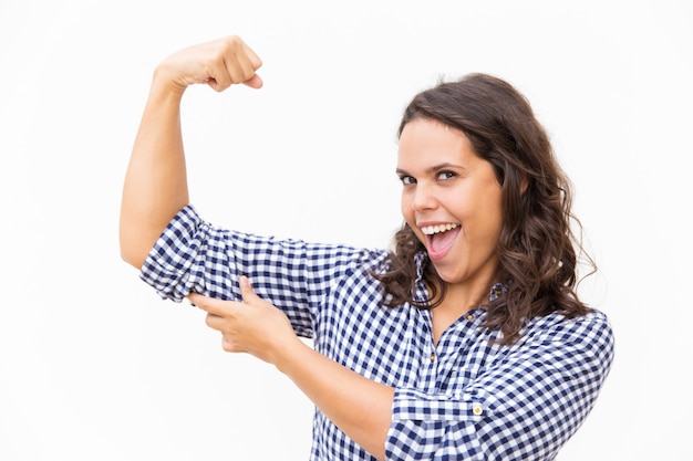 Mulher orgulhosa feliz mostrando o bíceps e sorrindo com a boca aberta