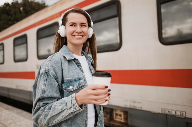 Mulher ouvindo música na plataforma do trem