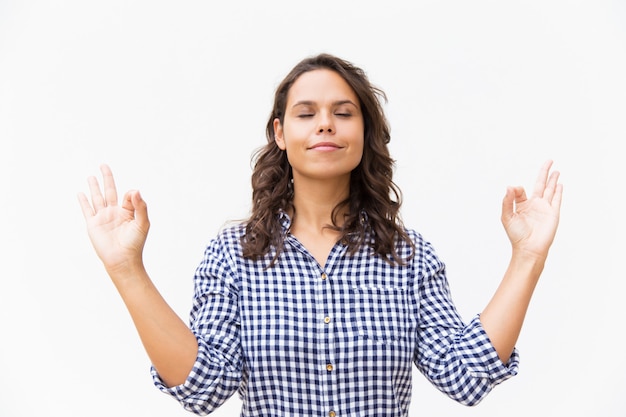 Mulher pacífica com os olhos fechados, fazendo o gesto de mão zen