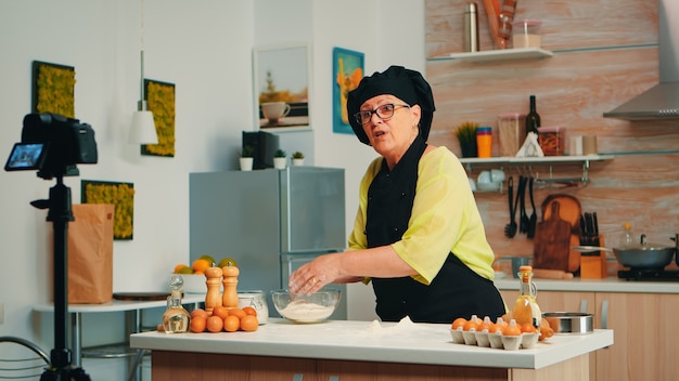 Foto grátis mulher padeiro apresentando receita durante a gravação de tutorial para mídia social. influenciador chef de blogueiro aposentado que usa tecnologia da internet para se comunicar, filmar, fazer um blog em podcast com equipamento digital