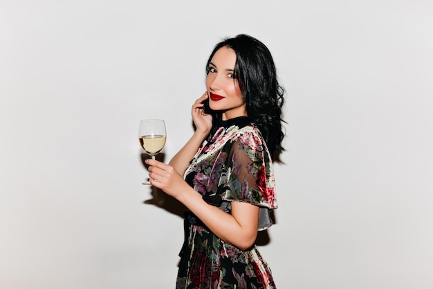 Mulher pálida com cabelo preto segurando uma taça de champanhe e sorrindo