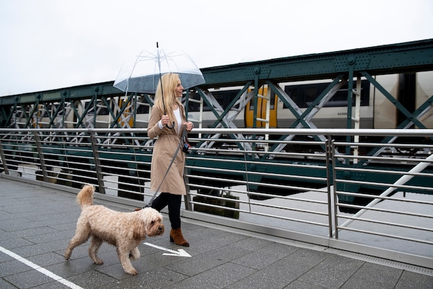 Mulher passeando com seu cachorro em uma ponte enquanto chove