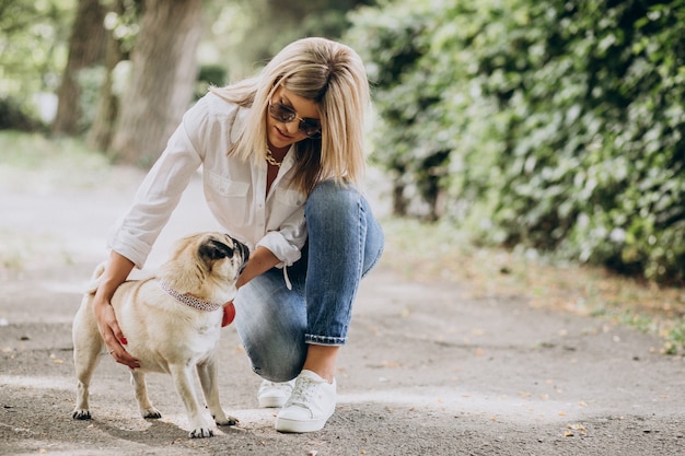 Mulher passeando no parque com seu cachorro pug