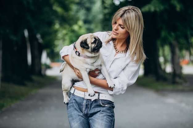 Mulher passeando no parque com seu cachorro pug