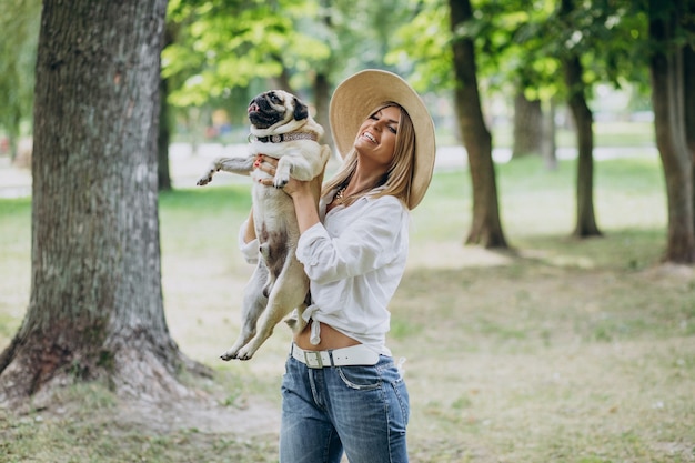 Mulher passeando no parque com seu cachorro pug