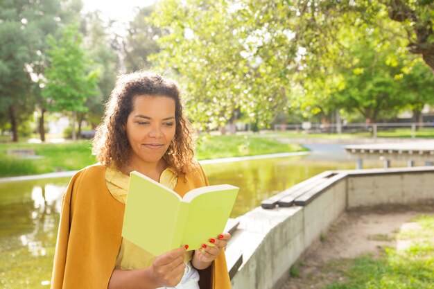 Mulher pensativa, aproveitando a leitura no parque