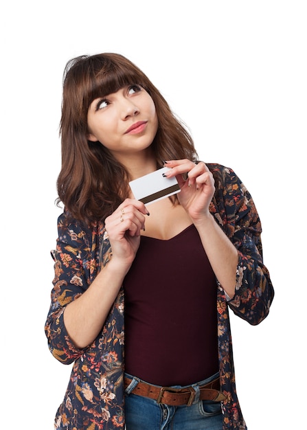 Mulher pensativa com um cartão de crédito