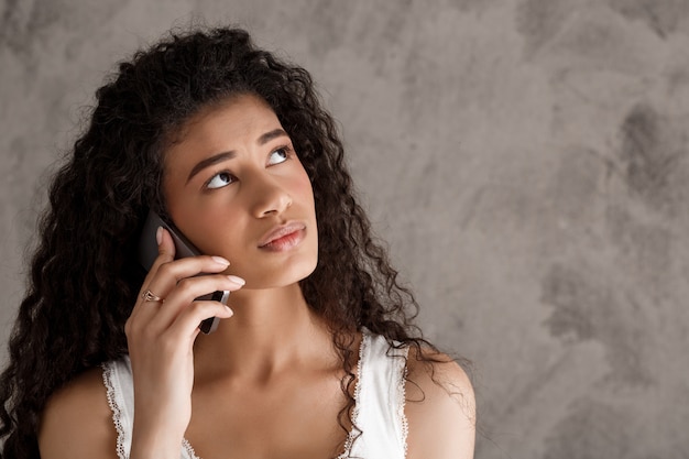 Mulher pensativa, falando no celular