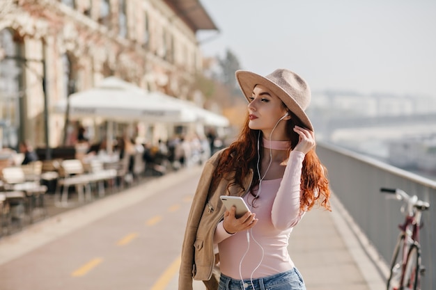 Mulher pensativa ouvindo música em fones de ouvido e apreciando a vista da cidade