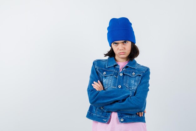 Mulher pequena em pé com os braços cruzados em camiseta e jaqueta jeans parecendo confiante