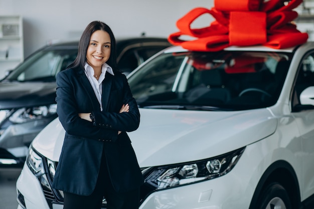 Mulher perto do carro com grande laço vermelho