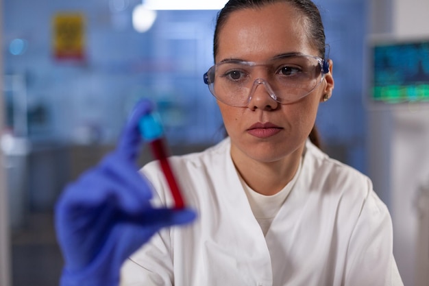 Mulher pesquisadora especialista segurando vacutainer com sangue infectado trabalhando na vacina bioquímica contra o coronavírus durante a pandemia global. Mulher especialista analisando amostra em laboratório de hospital