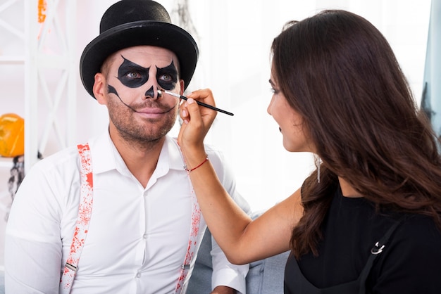 Mulher pintando seu homem para o halloween