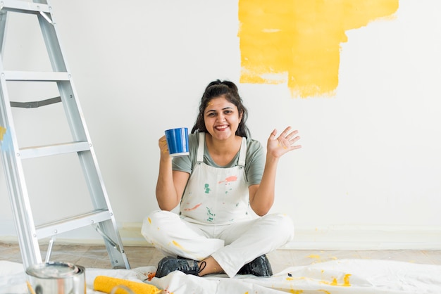Mulher pintando suas paredes amarelas