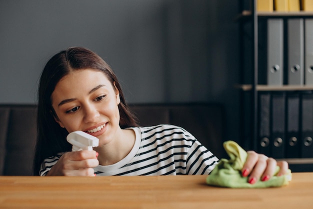 Mulher polindo a mesa em casa com spray