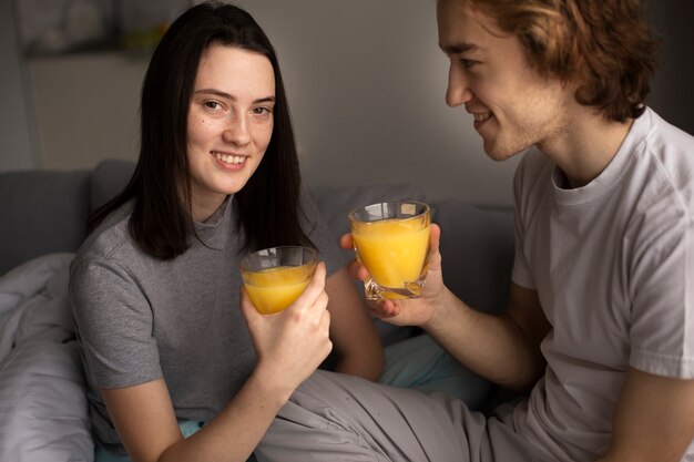 Mulher posando com suco de laranja e namorado