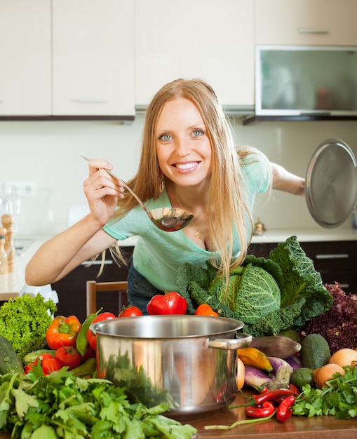 Foto grátis mulher positiva cozinhando com concha de vegetais crus