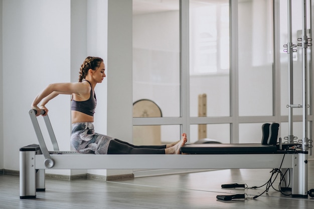 Mulher praticando pilates em um reformador de pilates