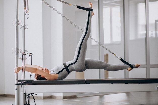 Mulher praticando pilates em um reformador de pilates